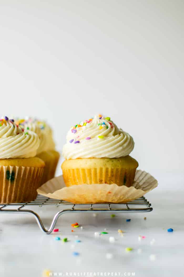 These are the softest and fluffiest vanilla cupcakes studded with rainbow sprinkles. Perfect for a birthday celebration! Find the recipe at runlifteatrepeat.com.