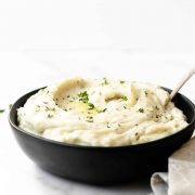 The best creamy slow cooker mashed potatoes infused with garlic and herbs. This recipe comes together seamlessly in the slow cooker. I make this simple Thanksgiving side dish every year and it's a guest favorite! #mashedpotatoes #slowcooker #thanksgiving #sidedish