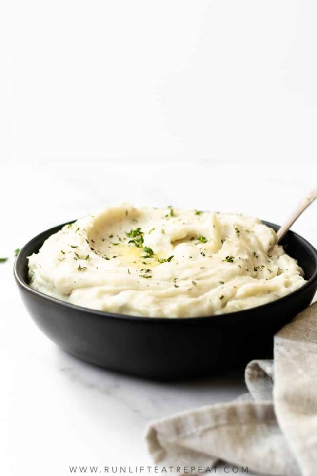 The best creamy slow cooker mashed potatoes infused with garlic and herbs. This recipe comes together seamlessly in the slow cooker. I make this simple Thanksgiving side dish every year and it's a guest favorite! #mashedpotatoes #slowcooker #thanksgiving #sidedish