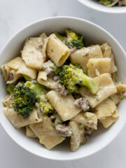 rigatoni pasta with sausage and broccoli with a cream sauce in a white bowl.