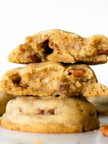 stacked brown butter pecan cookies on a white table.