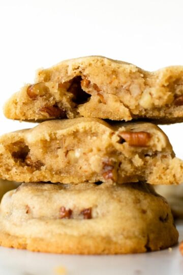 stacked brown butter pecan cookies on a white table.