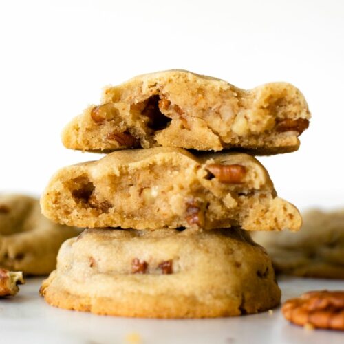 stacked brown butter pecan cookies on a white table.