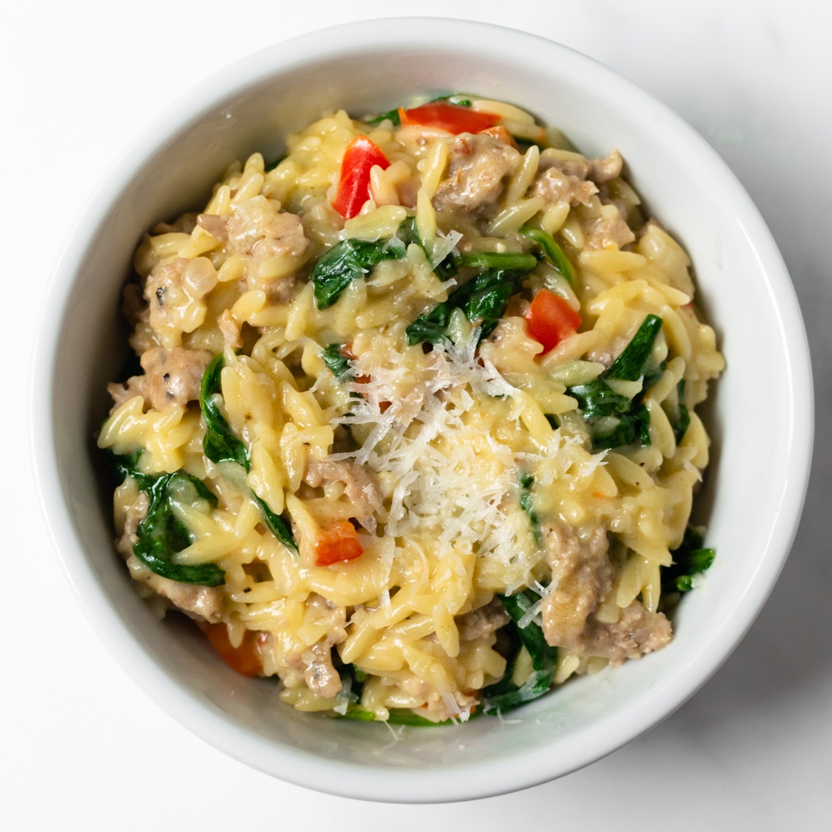 This one pan Italian sausage orzo is a quick and easy meal made with red bell peppers, onions, garlic, orzo, chicken broth, cream, parmesan, and spinach. It's perfect for busy weeknights— minimal effort and minimal clean up!