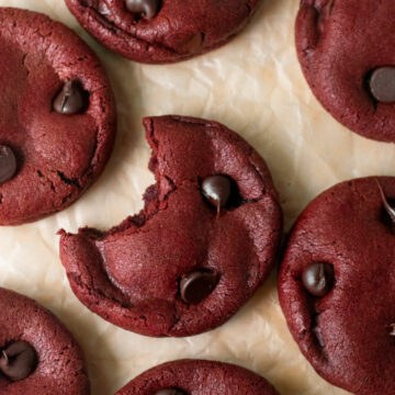 a bite taken from a red velvet cookie on parchment paper