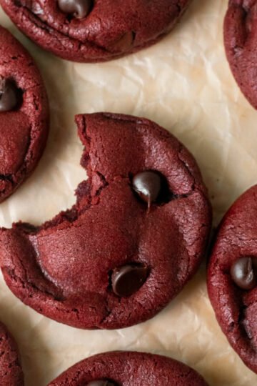 a bite taken from a red velvet cookie on parchment paper