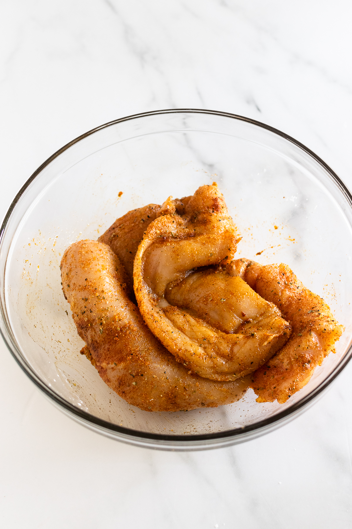 chicken breasts in a bowl coated in spices