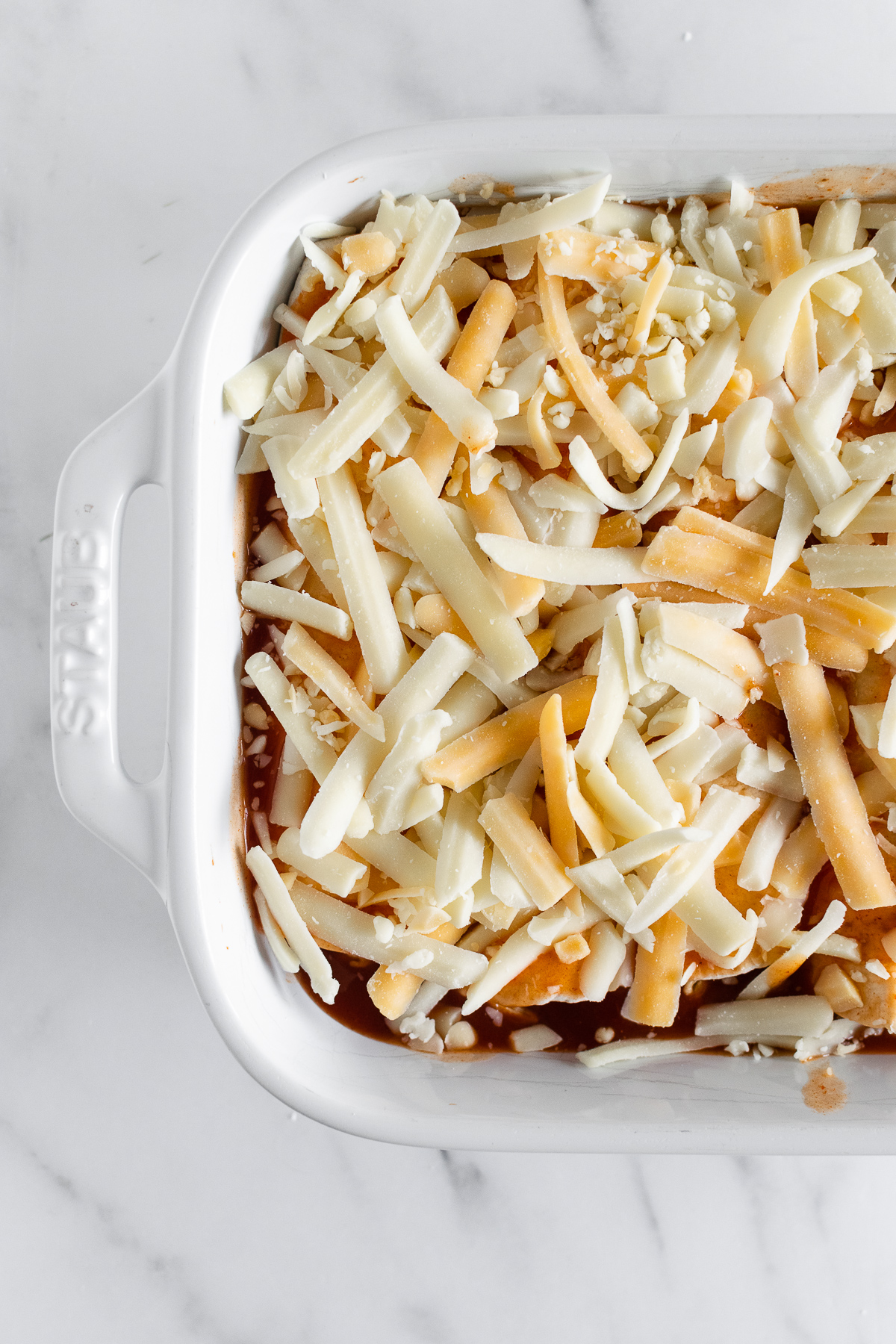 chicken enchiladas topped with cheese in a baking dish
