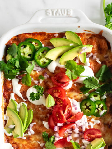 easy chicken enchiladas in a white baking dish with toppings