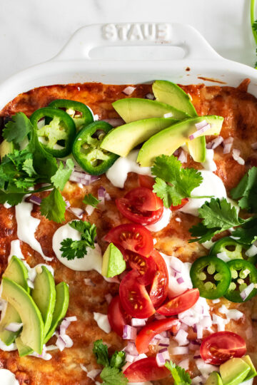 easy chicken enchiladas in a white baking dish with toppings