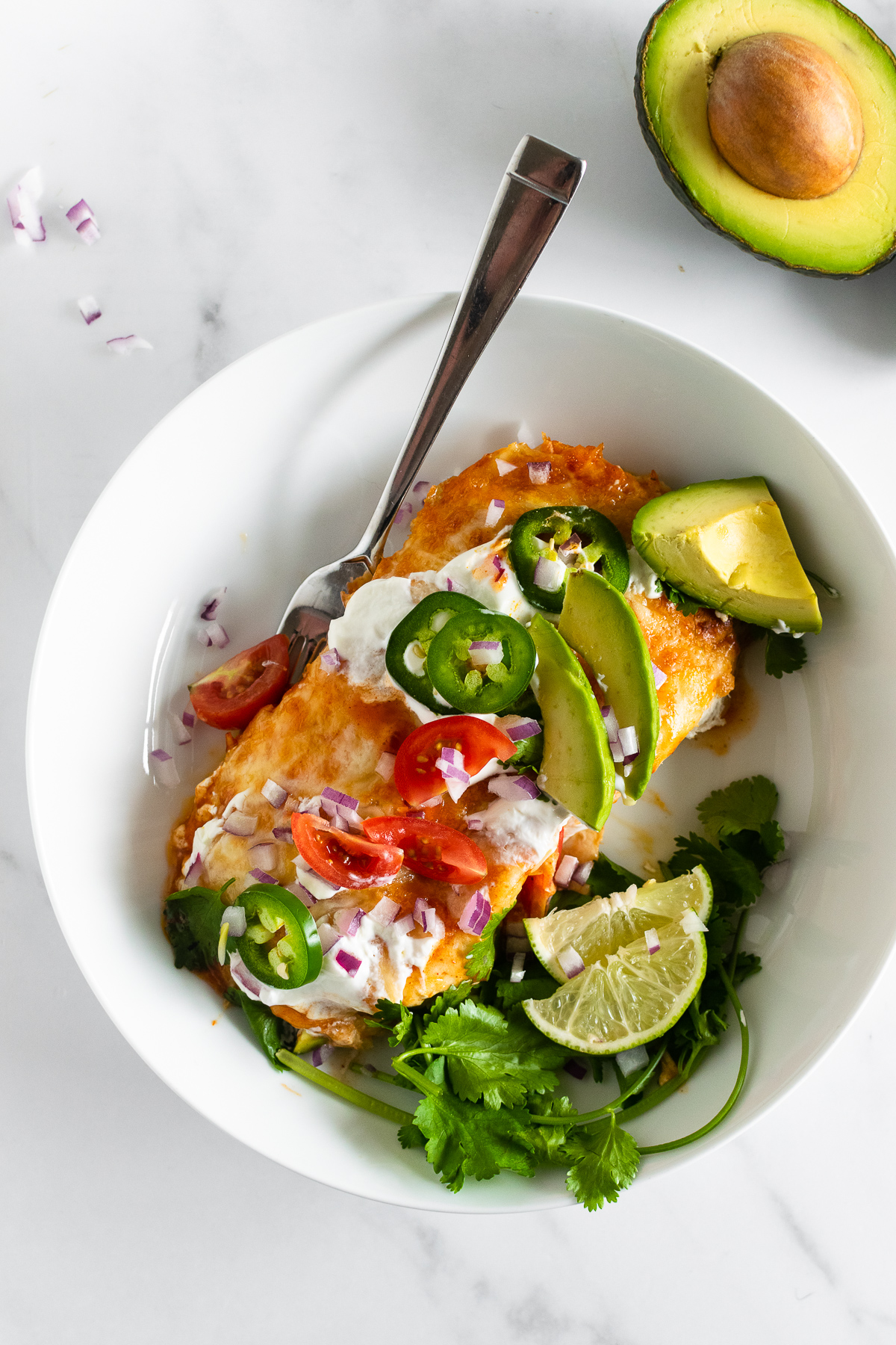 cream cheese chicken enchiladas in a bowl with toppings and a fork