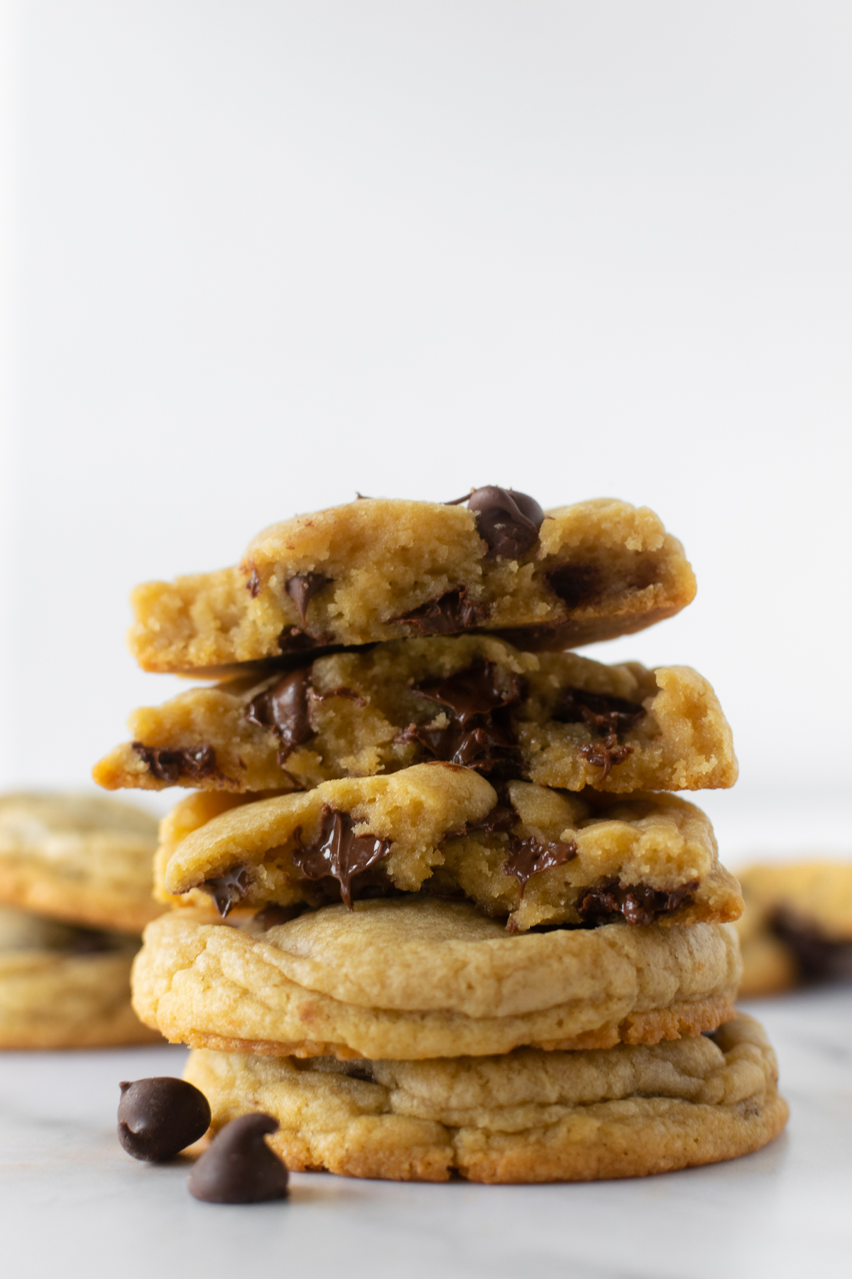 stacked chocolate chip cookies on a white counter.