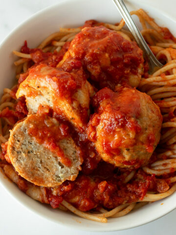 Try my easy homemade baked chicken parmesan meatballs recipe– a twist on the classic chicken parmesan we all know and love. Seasoned just right, the chicken meatballs are covered in tomato sauce and baked in the oven producing incredibly tender, flavorful meatballs (and sauce) with hardly any work! Finished off with shredded mozzarella cheese on top. If you can roll meatballs, you can make this chicken parmesan meatball recipe.