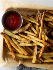 crispy baked french fries on a baking sheet with parchment paper with ketchup.