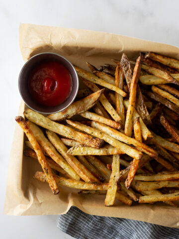 crispy baked french fries on a baking sheet with ketchup.