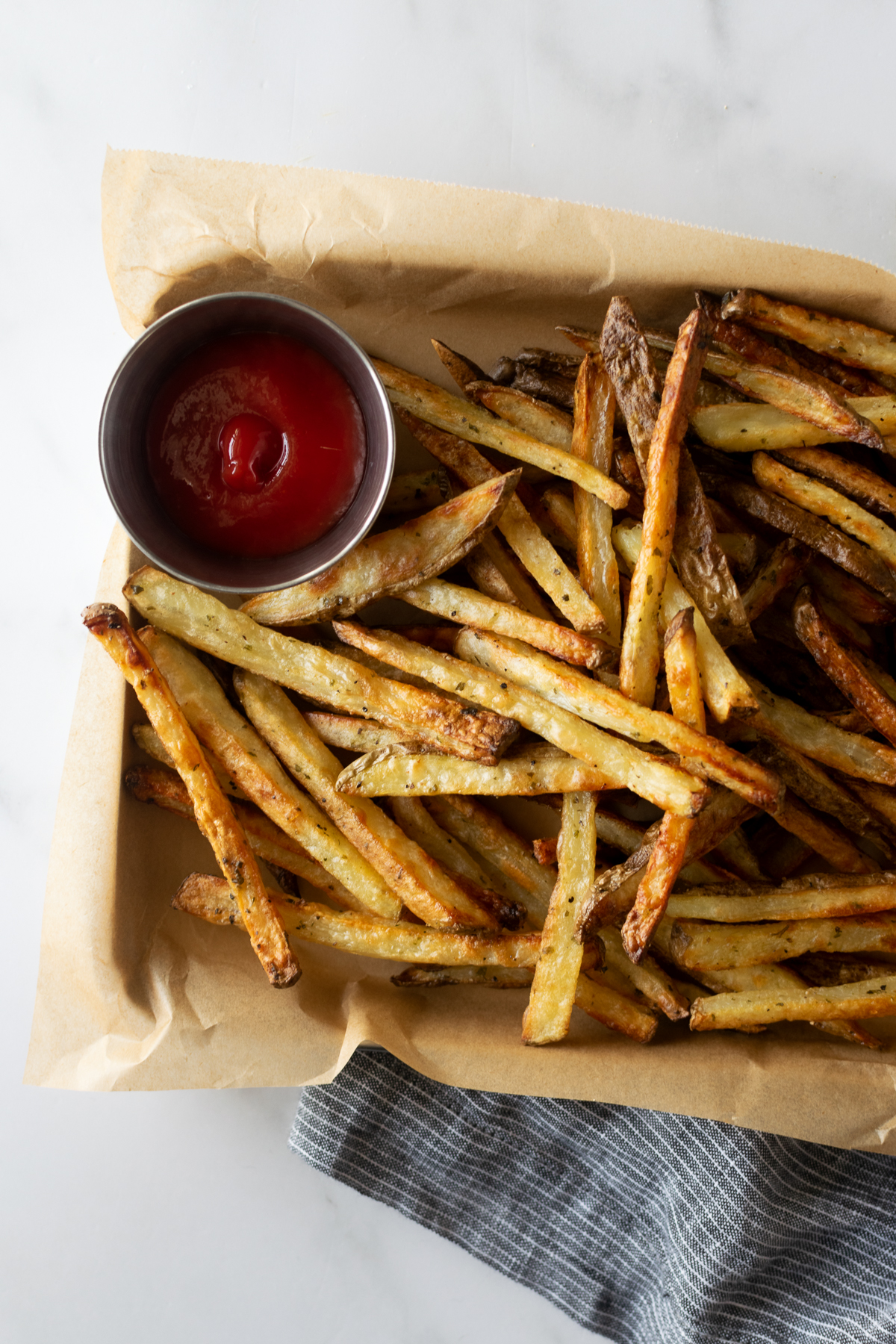 crispy baked french fries on a baking sheet with parchment paper with ketchup.
