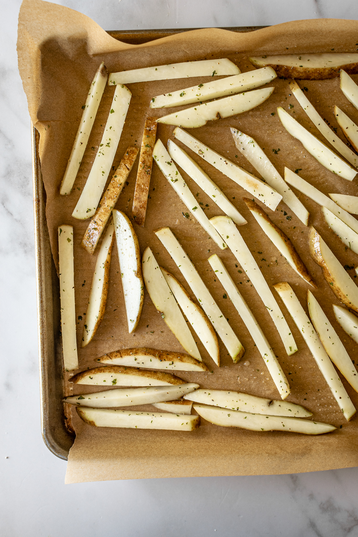 french fries on a baking sheet with parchment paper before baking.