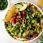 mexican 7 layer dip in a white bowl with chips.