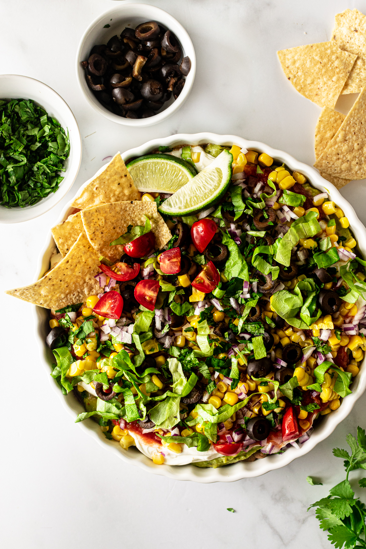 mexican 7 layer dip in a white bowl with chips.