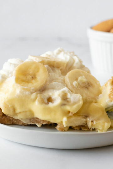 slice of banana pudding pie on a white plate with fork.