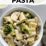rigatoni pasta with sausage and broccoli with a cream sauce in two white bowls with a napkin.