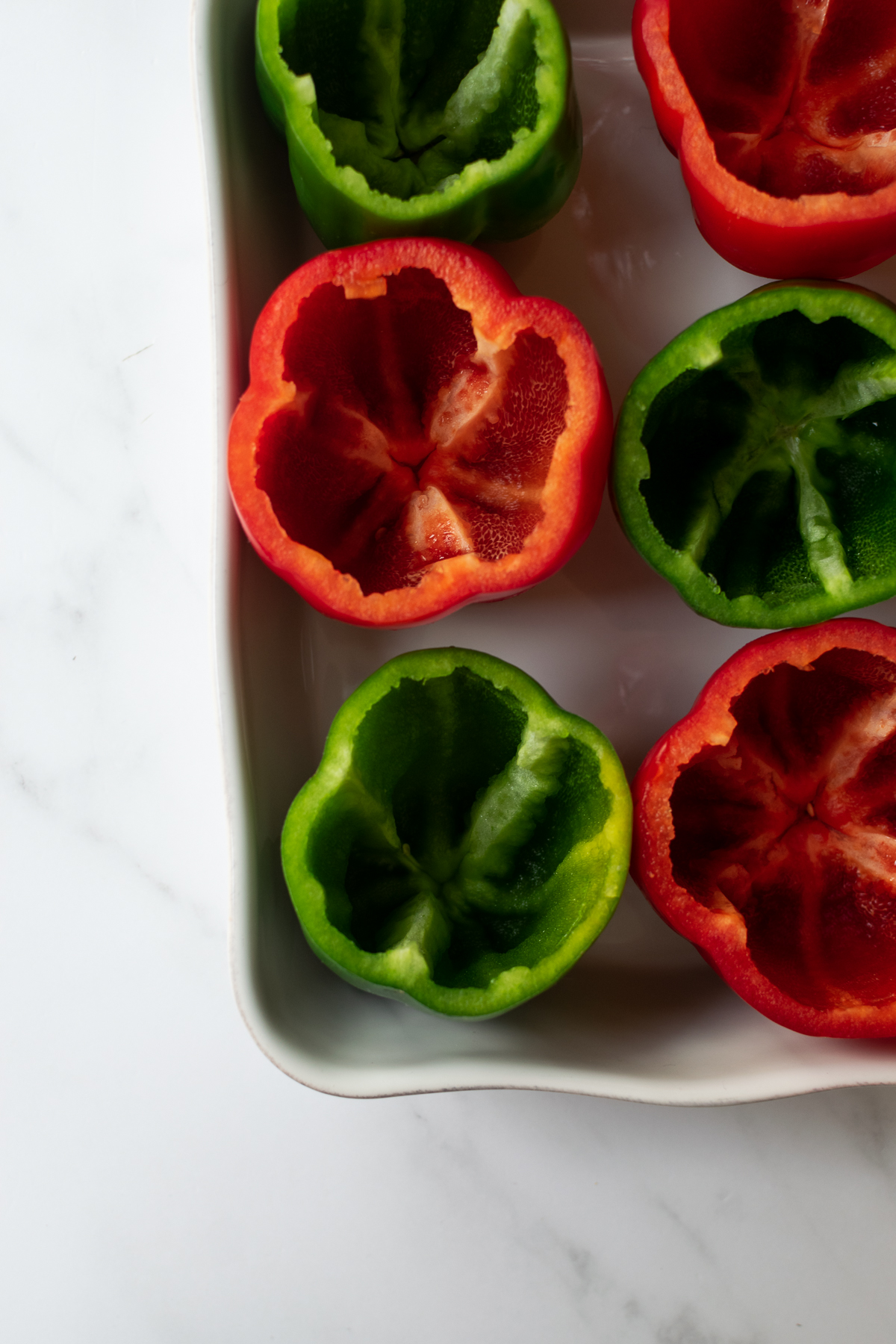topped bell peppers in a white baking dish.