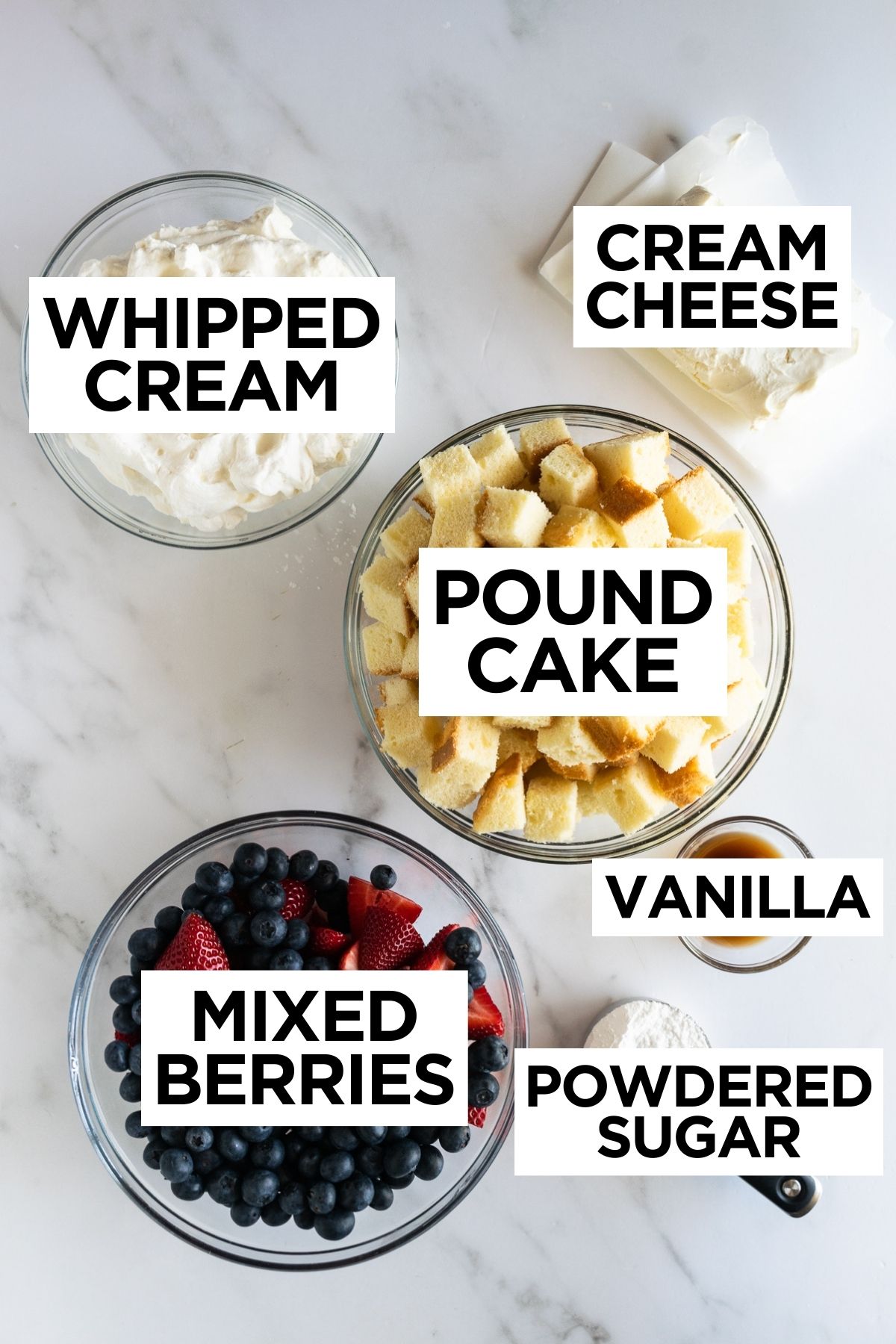 ingredients for berry trifle in bowls such as pound cake, cream cheese, vanilla, sugar, whipped cream and berries.