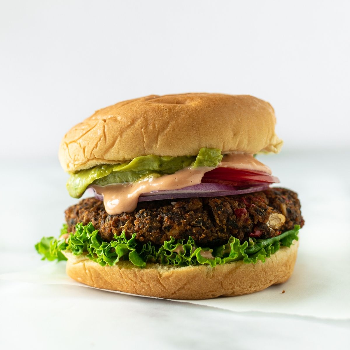 veggie burger topped with lettuce, tomato, onion, special sauce, and guacamole.