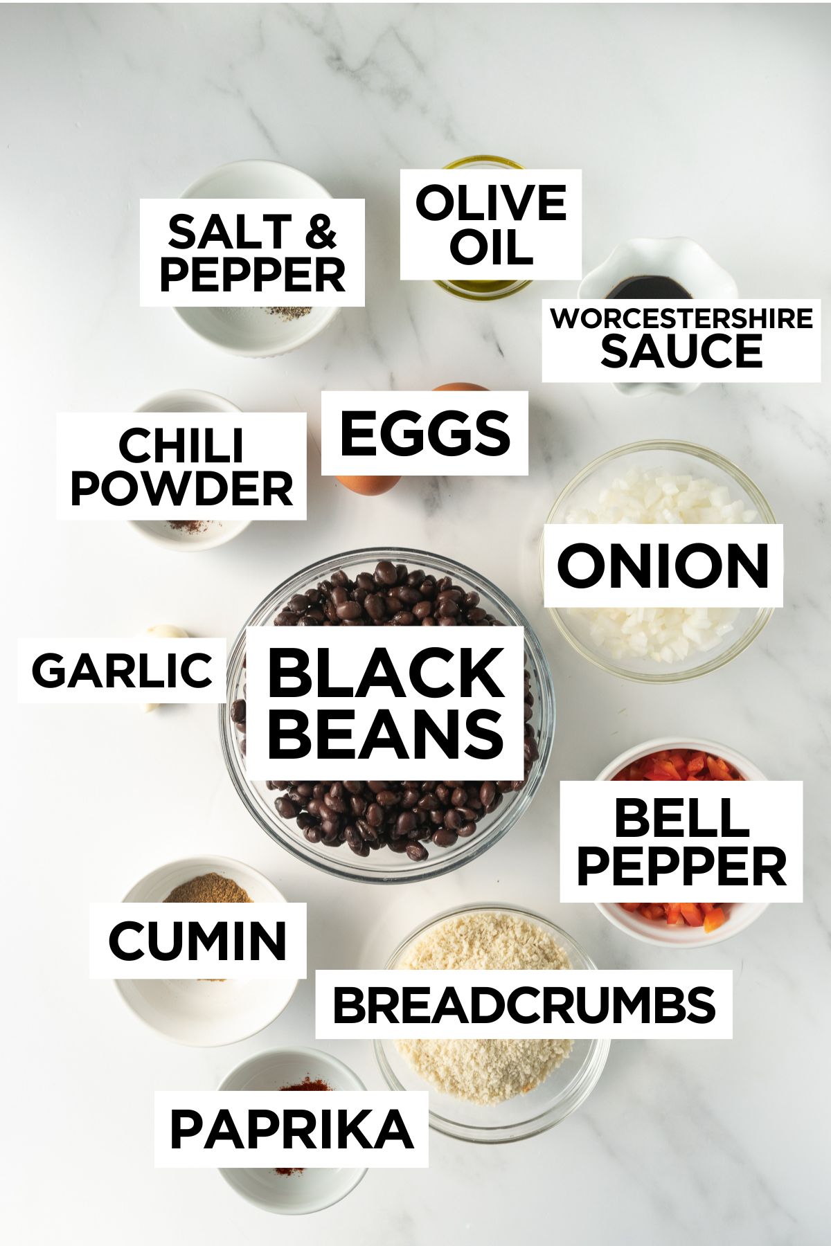 ingredients for black bean burgers in bowls on a white table such as black beans, pepper, onion, etc.