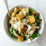 chicken caesar pasta salad in a white bowl with a fork.