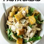 chicken caesar pasta salad in a white bowl with a fork with text overlay.