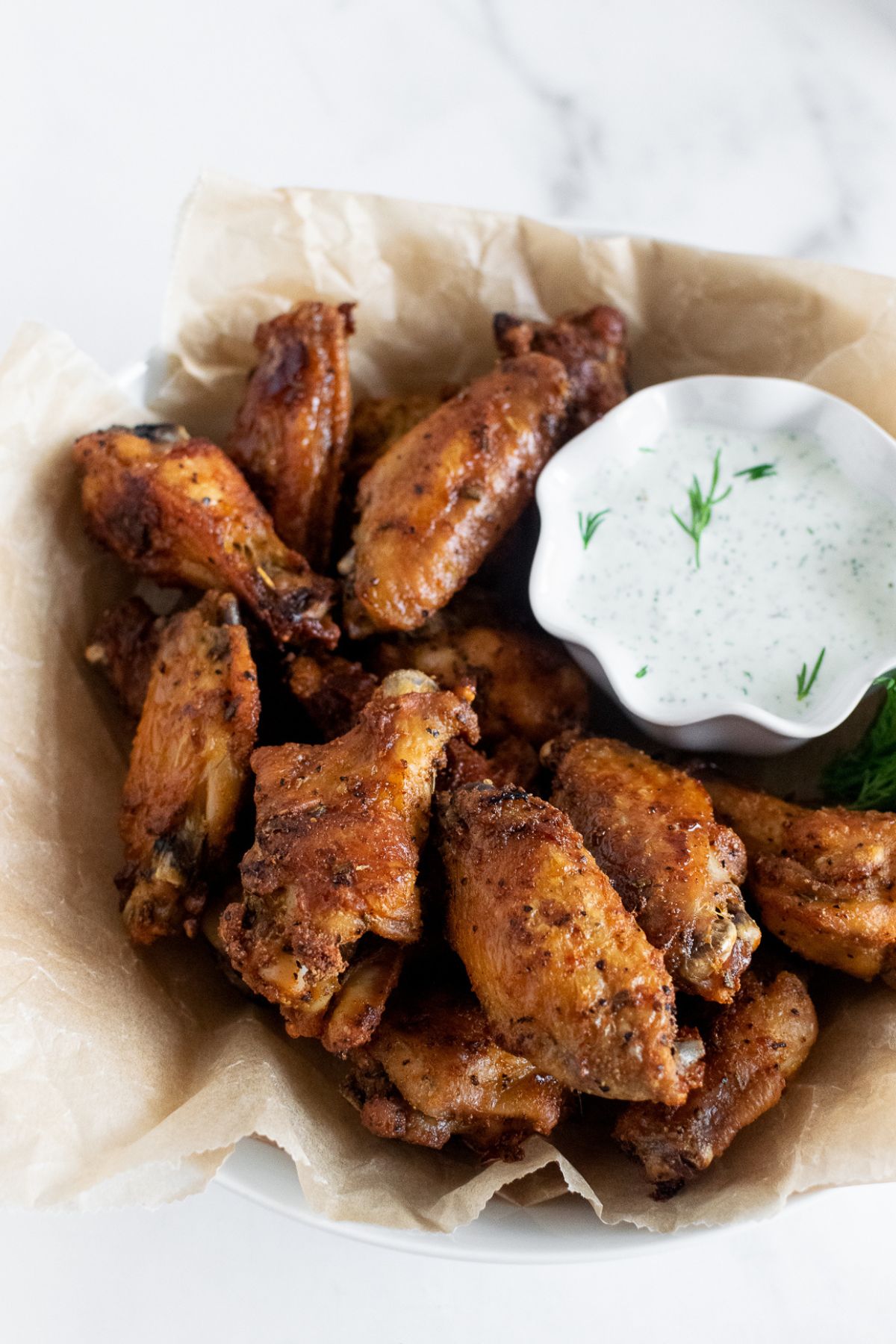 crispy baking chicken wings in a bowl with ranch dressing.