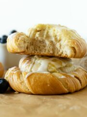 cream cheese danish stacked with a bite on parchment paper.