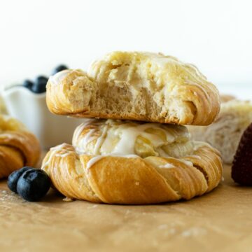 cream cheese danish stacked with a bite on parchment paper.