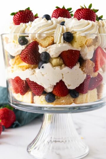 berry trifle in a glass trifle dish with pound cake, cheesecake filling, berries and whipped cream.