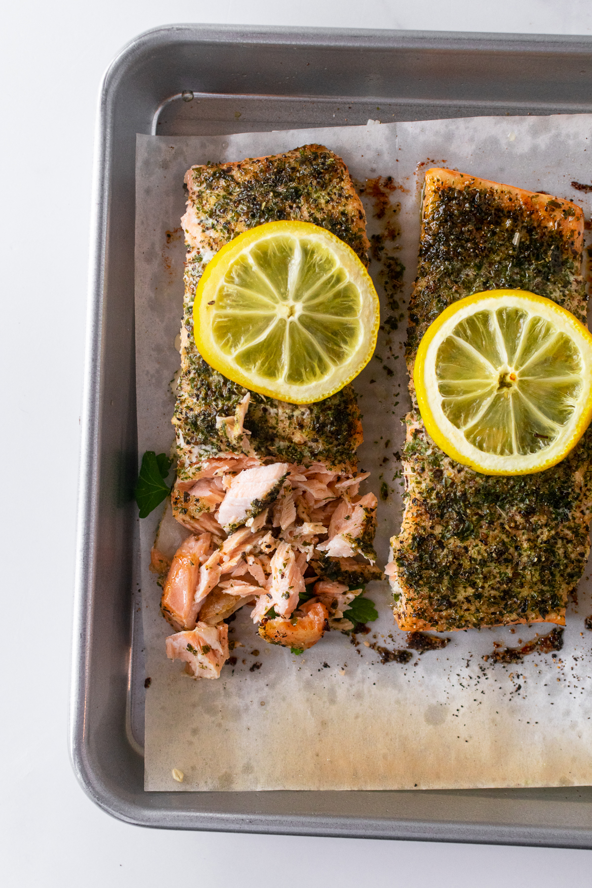 baked salmon on a baking sheet topped with sliced lemon.