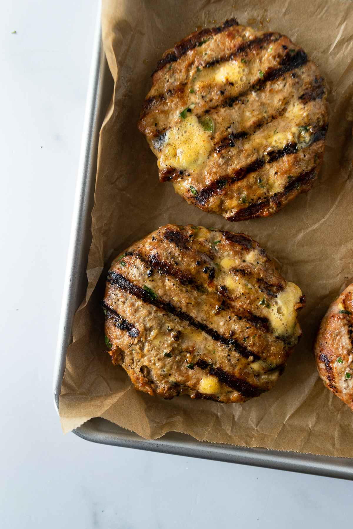 cooked jalapeno turkey burgers on a baking sheet lined with parchment paper.