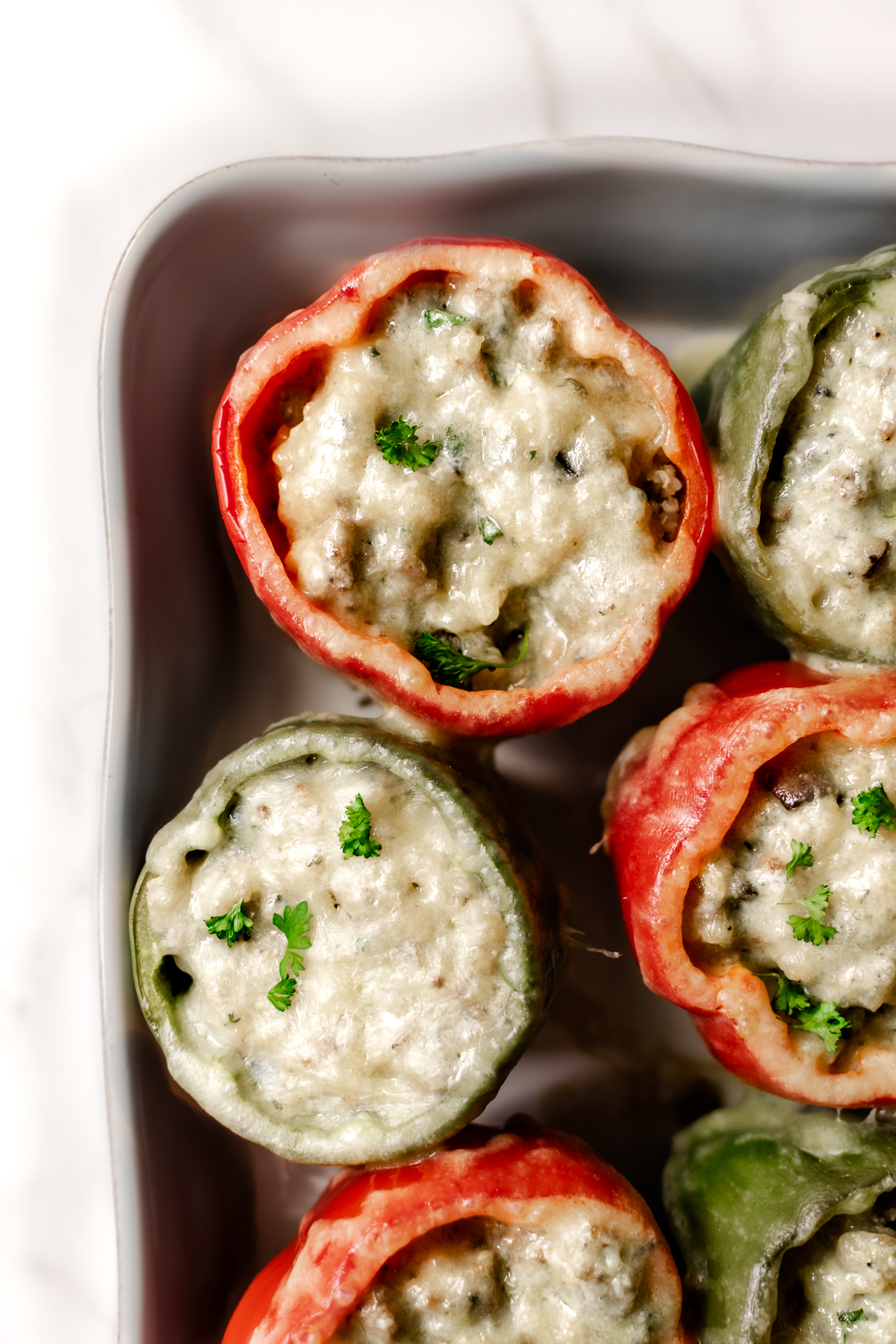 stuffed bell peppers topped with melted cheese in a white baking dish.