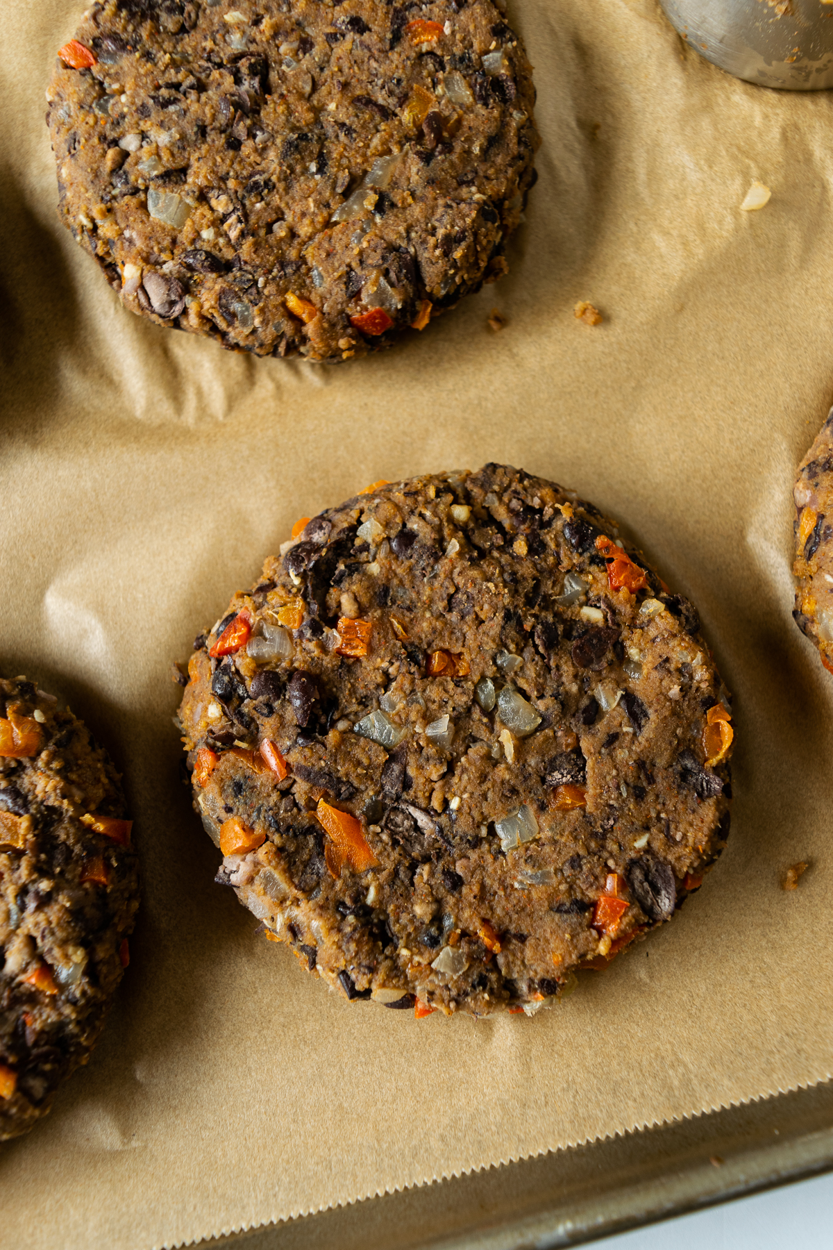 shaped uncooked black bean burgers on a baking sheet with parchment paper.