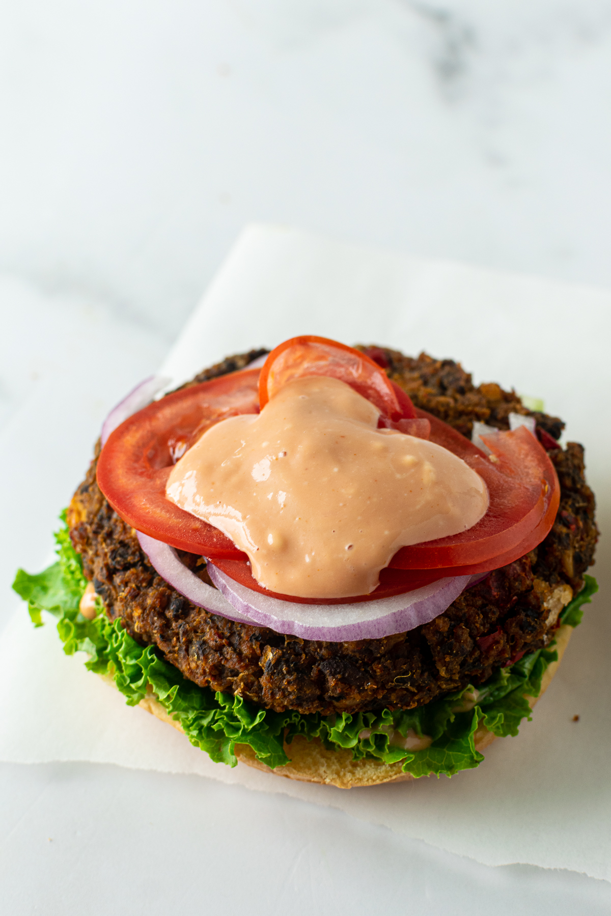 lettuce, tomato, onion and secret sauce on top of a veggie burger.