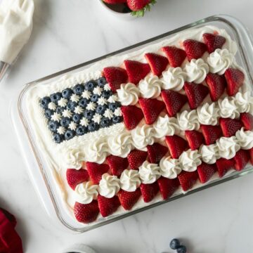 4th of July cake as American flag cake in a baking pan topped with strawberries and blueberries.