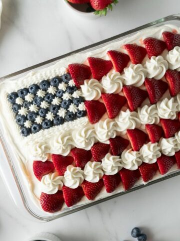 4th of July cake as American flag cake in a baking pan topped with strawberries and blueberries.