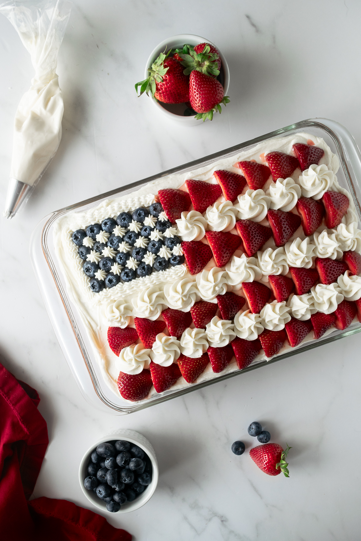 4th of July cake as American flag cake in a baking pan topped with strawberries and blueberries.