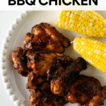 baked bbq chicken and corn on the cob on a white plate.