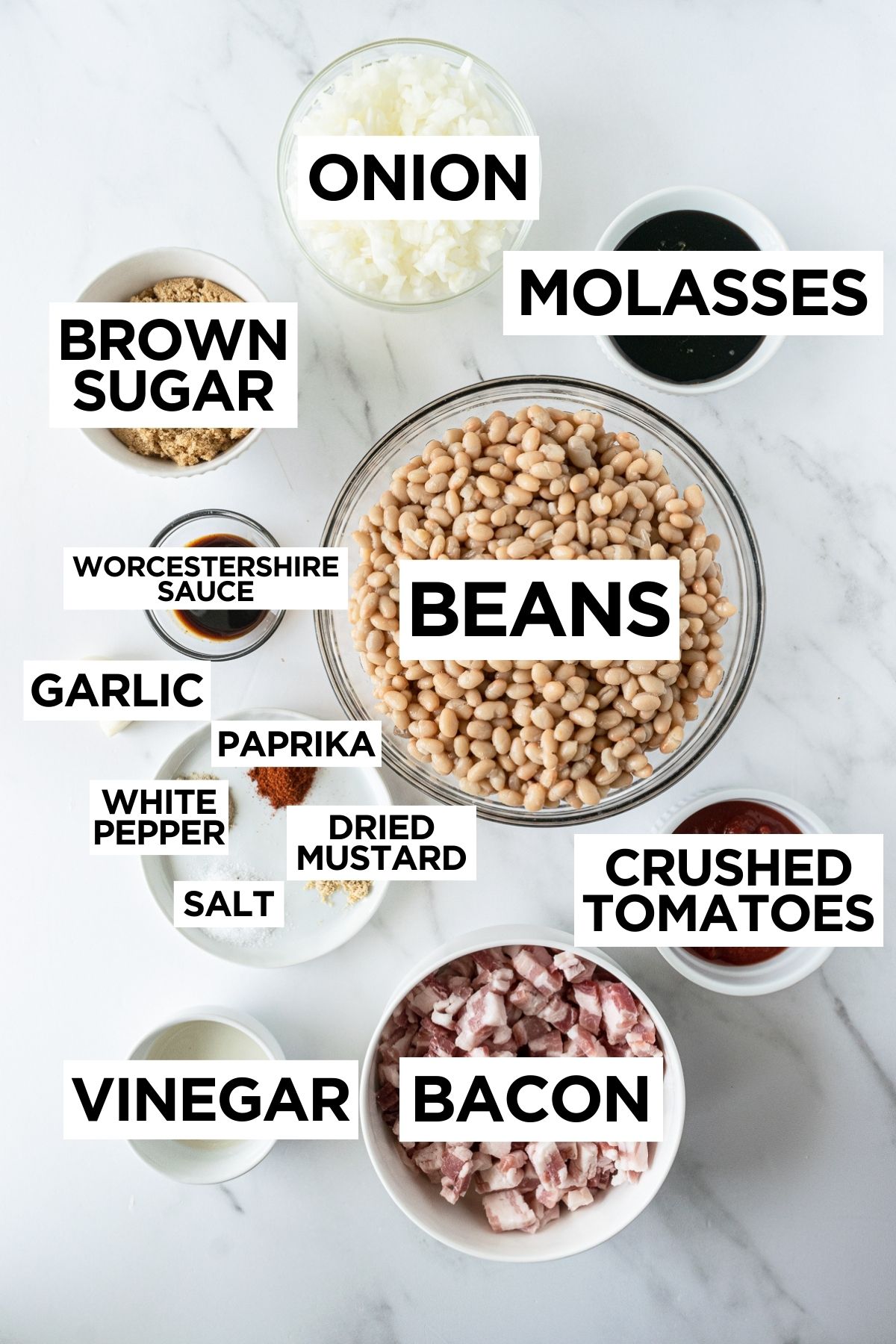 ingredients for baked beans in bowls on a white table.