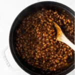 baked beans in a black pot with a wooden spoon.