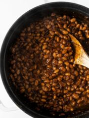 baked beans in a black pot with a wooden spoon.
