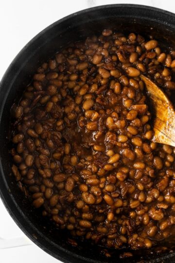 baked beans in a black pot with a wooden spoon.