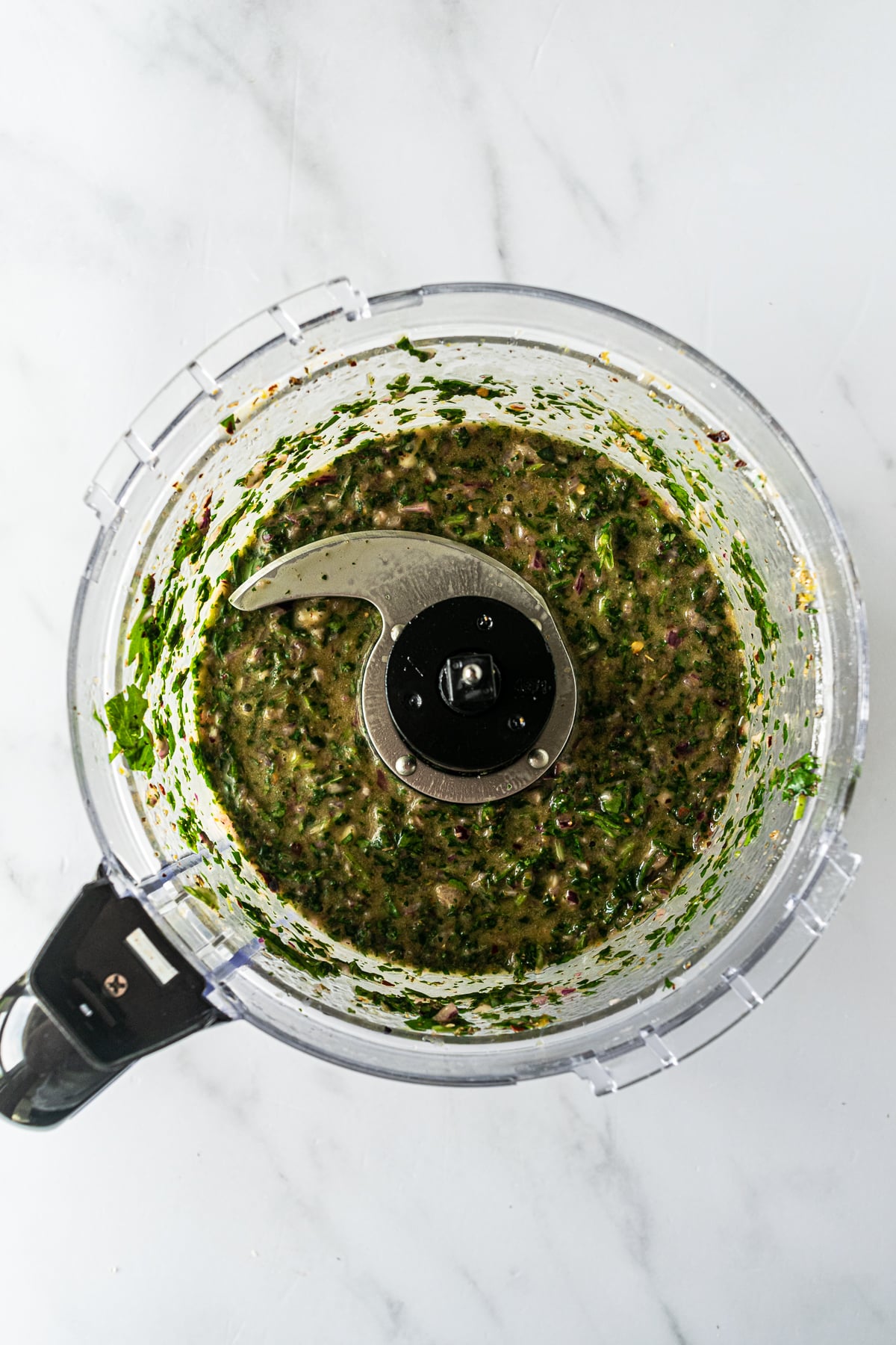 blended ingredients for chimichurri in a food processor.