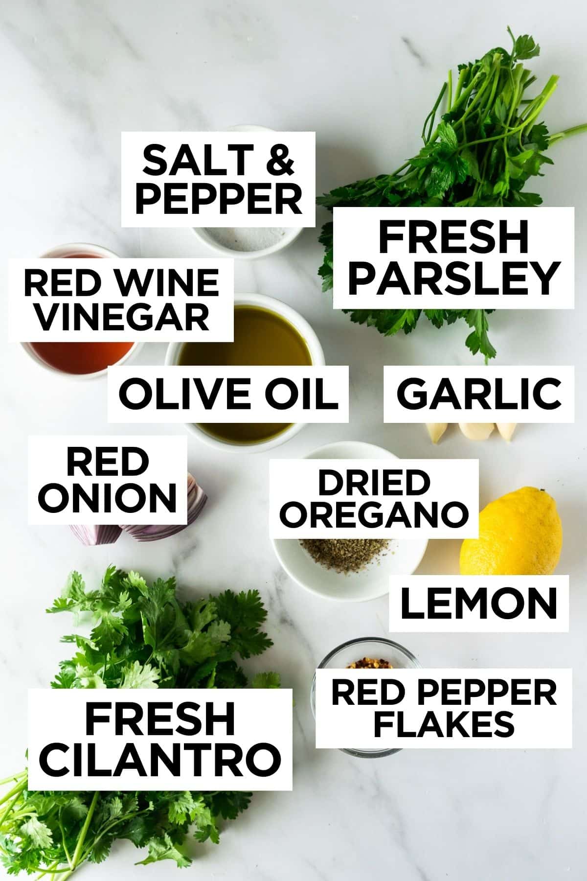 ingredients for chimichurri sauce in bowls on a white table.